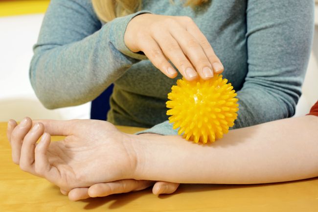 Ergotherapie Frau rollt Igelball über Unterarm einer Person